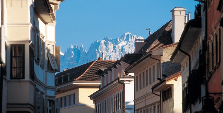 Imposant blicken die Bergsilhouetten und verschneiten Berggipfel hinter den Häusern der Bozner Altstadt hervor